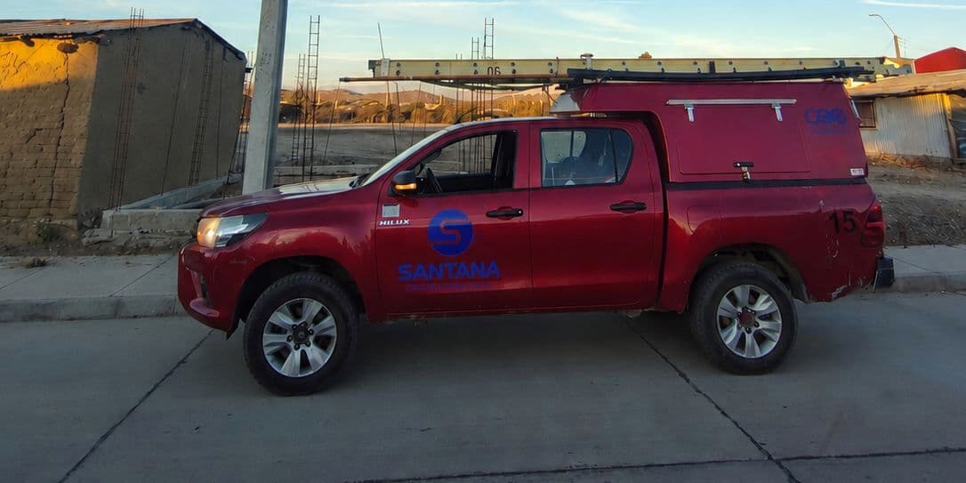 Camioneta Toyota Hilux rotulada con el logo de Santana, junto a una línea eléctrica de baja tensión.