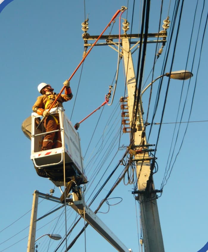 Brigada de Santana trabajando en altura sobre canastillo en una línea eléctrica de baja tensión.